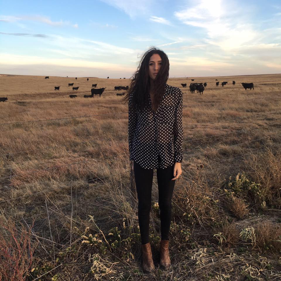 Lauren standing in a field with livestock in the background